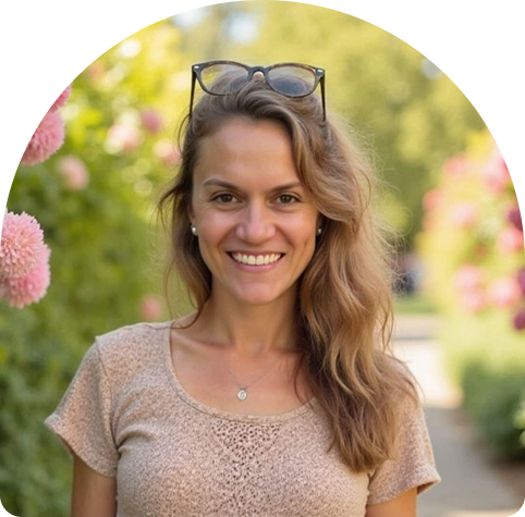 Emma Jackson, personal trainer and remedial masseuse, smiling in a garden setting with flowers, embodying warmth and approachability in wellness services.
