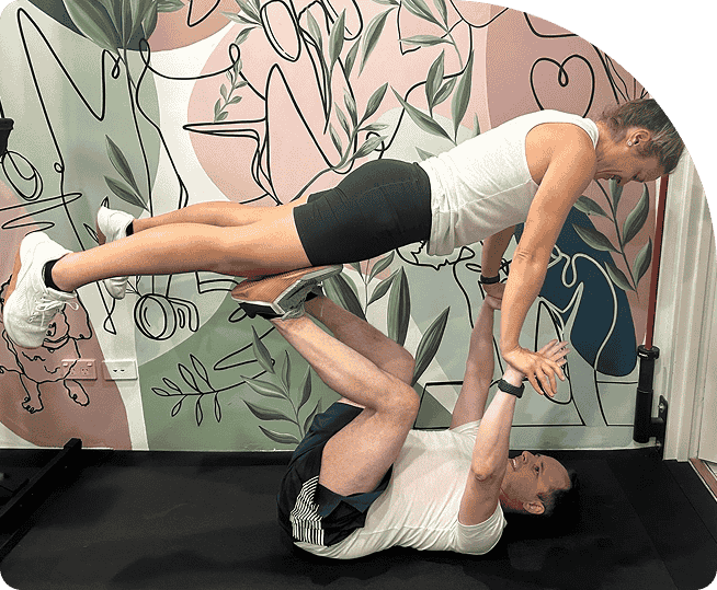 Person performing partner exercise in a fitness studio, emphasizing strength training and mobility, surrounded by a colorful abstract mural.