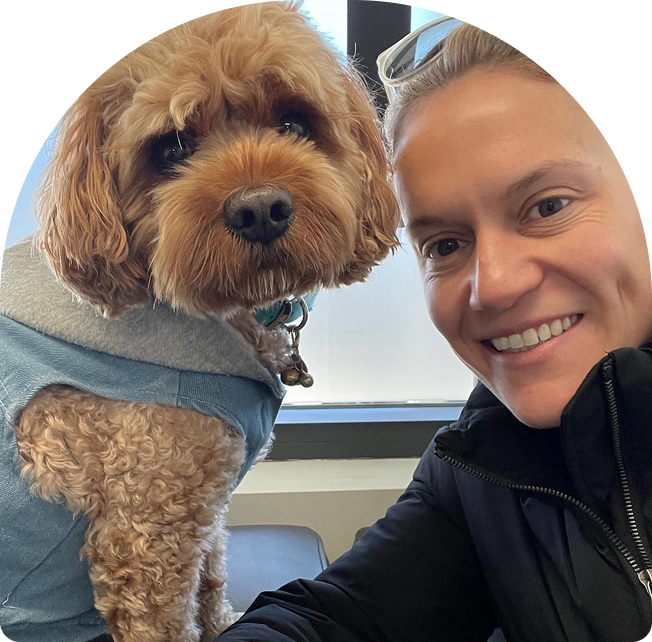Emma Jackson smiling with a dog in a cozy indoor setting, emphasizing her approachable personality and connection to wellness.
