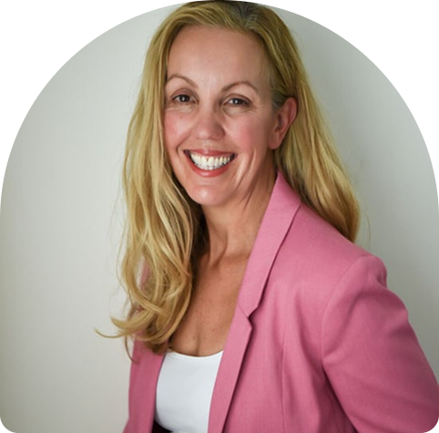 Emma, a wellness practitioner at Wellness on Shore, smiling warmly in a pink blazer, embodying a supportive and encouraging presence for her clients.