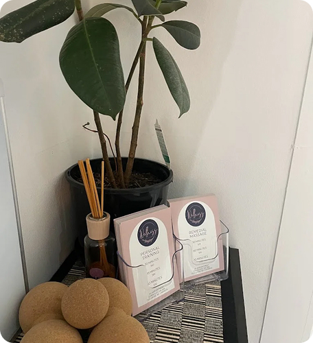 Wellness on Shore treatment room display featuring personal massage and personal training brochures, a potted plant, essential oil bottle, and decorative orbs.