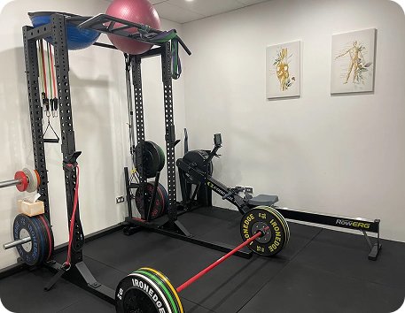 Gym space at Wellness on Shore featuring weightlifting equipment, resistance bands, and a rowing machine, promoting fitness and wellness activities.