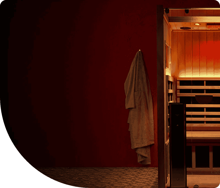 Infrared sauna with warm lighting, wooden interior, and a hanging robe, emphasizing a relaxing and therapeutic environment for wellness and detoxification.