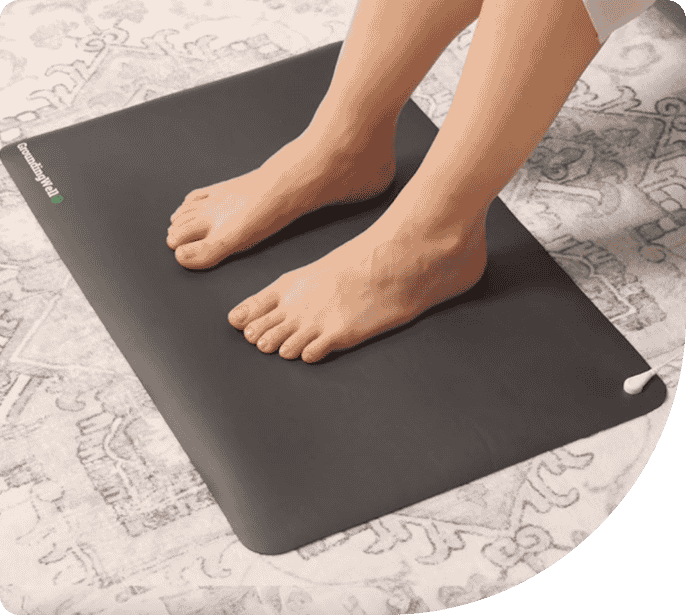 Feet standing on a grounding mat, designed to reconnect the body to natural earth energy, promoting wellness and balance.