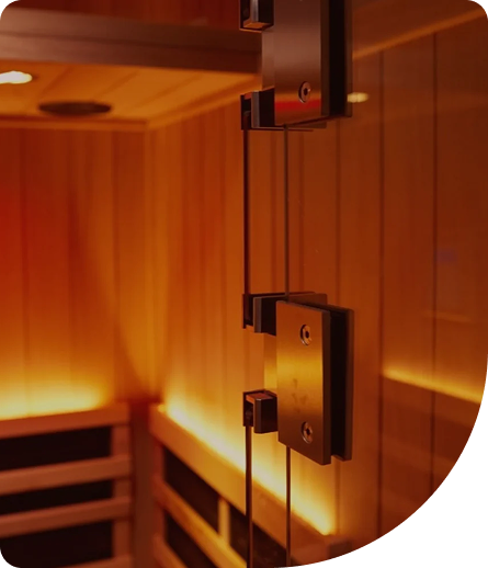Infrared sauna interior with warm lighting, featuring wooden panels and glass door hinges, promoting relaxation and recovery.
