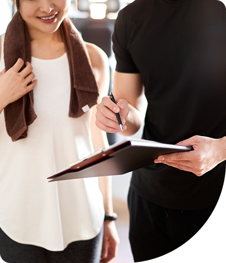 Person in fitness attire discussing personalized training program with trainer, showcasing supportive atmosphere and focus on health and wellness.