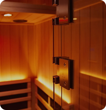Infrared sauna interior featuring wooden panels, soft ambient lighting, and glass door hardware, emphasizing relaxation and detoxification for wellness sessions at Wellness On Darling.