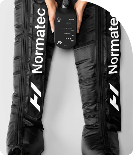 Normatec compression therapy boots in use, designed for recovery and muscle relaxation, with a control unit held by a user, highlighting wellness and recovery services.