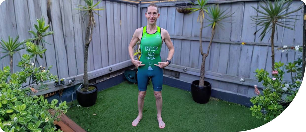 Athlete showcasing Team Australia kit with "TAYLOR AUS RPG" printed on the front, standing in a garden setting surrounded by plants, representing pride and community support in sports.