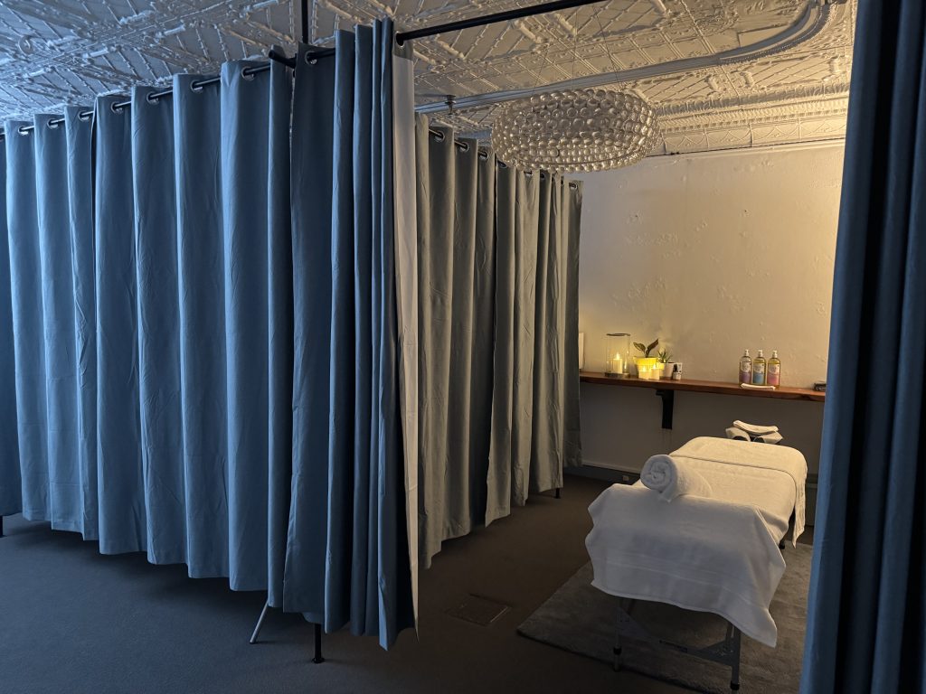 Wellness on Shore treatment room with massage table, soft lighting, candles, and privacy curtains.
