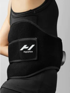 Hyperice Venom 2 heat and vibration therapy wrap on a person's lower back, illustrating muscle recovery support.