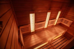 Infrared sauna interior with wooden benches and heating panels, showcasing a warm and inviting wellness environment for muscle recovery and relaxation.