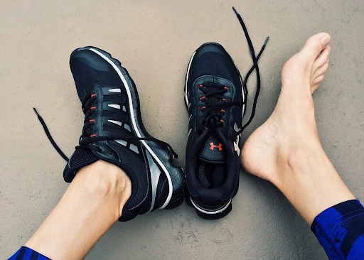 Footwear for athletic performance, showcasing a black running shoe and a bare foot, emphasizing mobility and comfort in relation to plantar fasciitis treatment and relief strategies.