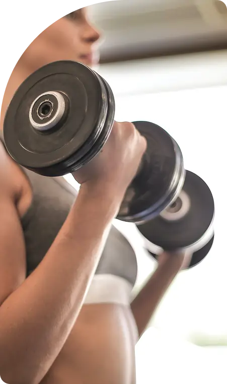 Woman lifting a dumbbell in a fitness setting, emphasising strength training and wellness.