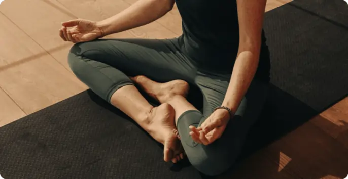 Person practising yoga in a calm setting, seated cross-legged on a mat, emphasising mindfulness and relaxation, reflecting Wellness On Shore's focus on movement and wellbeing.